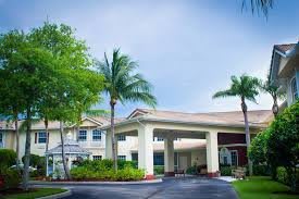A building with palm trees and landscaped grounds at the entrance.
