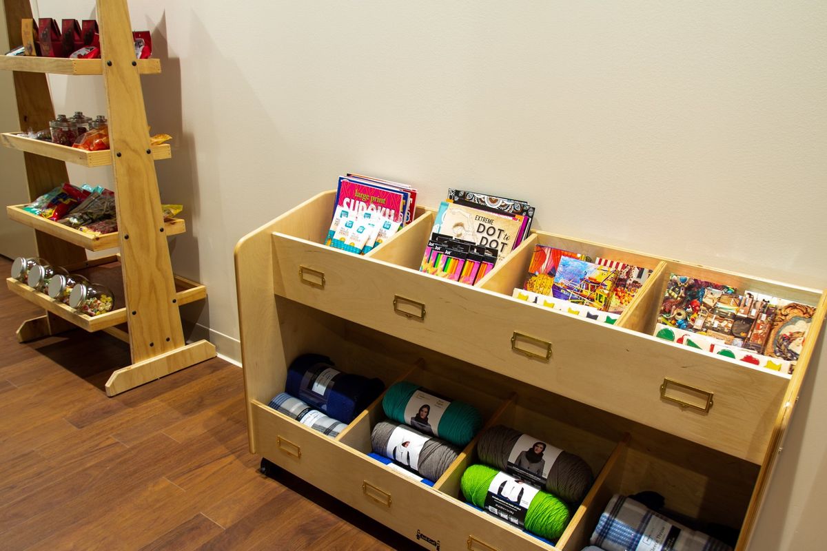 A well-organized wooden shelf displaying children's books and colorful yarn.