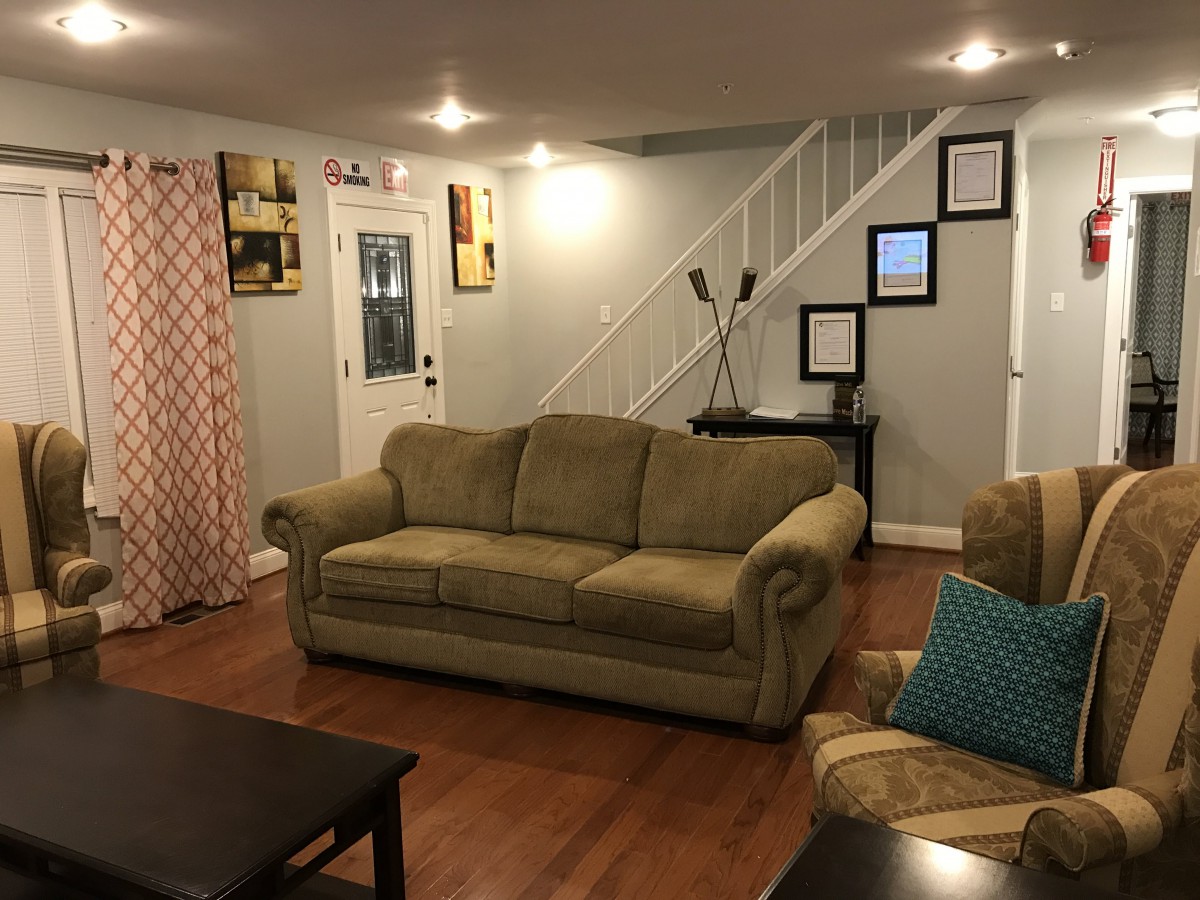 A cozy living room with a sofa, coffee table, and a staircase leading to the upper floor.