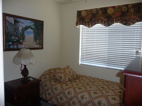 A cozy bedroom with a single bed, a lamp on the nightstand, and a painting on the wall.