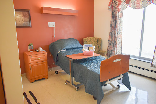 A cozy hospital room featuring a neatly made bed, a bedside table, and soft curtains.