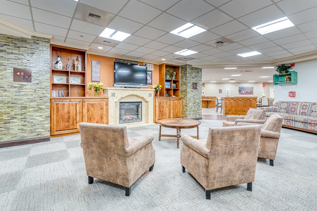 A cozy lobby or reception area featuring a fireplace, bookshelves, and comfortable seating.