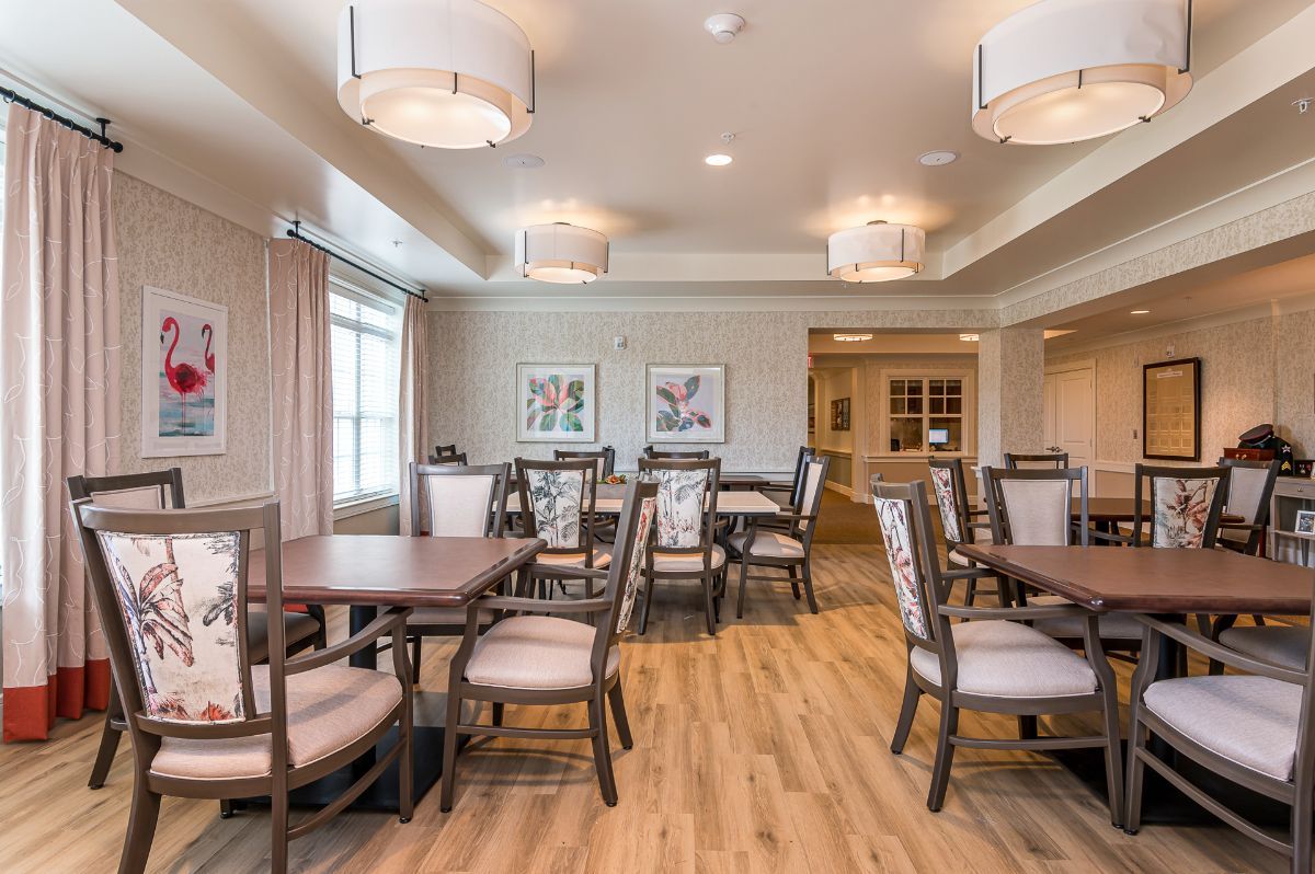 A spacious dining room with neatly arranged tables and chairs, featuring modern lighting and decor.