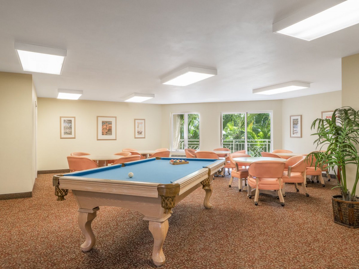 A well-lit recreation room featuring a pool table and seating area.