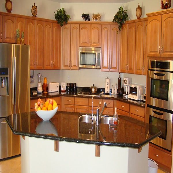 A modern kitchen featuring stainless steel appliances, wooden cabinets, and a granite countertop with an island.