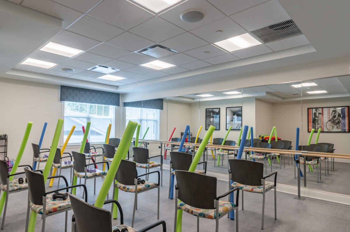 An empty classroom with colorful pool noodles placed on the chairs.