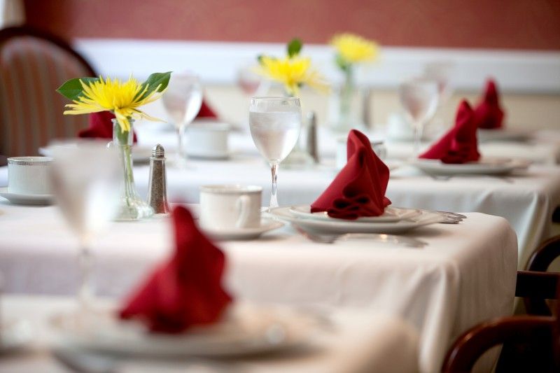 An elegantly set table with red napkins and yellow flower centerpieces.