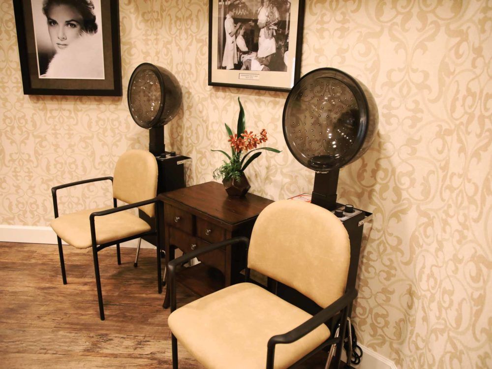 A cozy waiting area in a salon featuring vintage hair dryers and stylish seating.