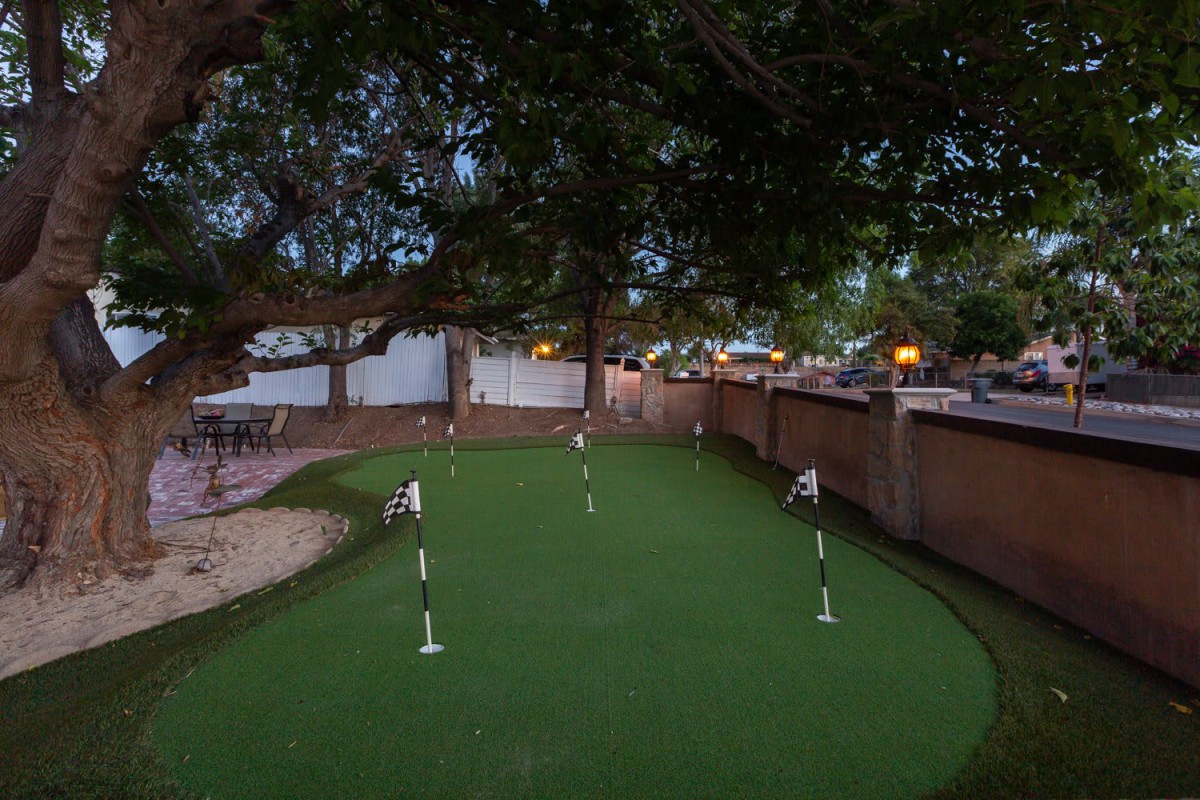 An outdoor putting green set amidst trees during the evening.