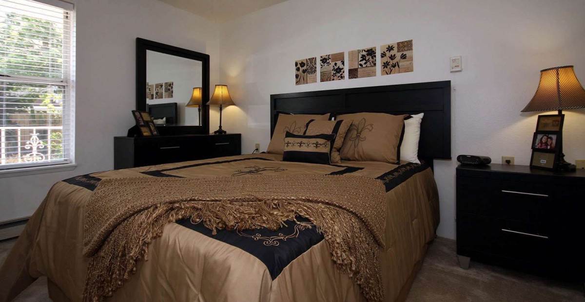 A cozy and well-decorated bedroom with elegant bedding, a mirror, and ambient lighting from lamps.