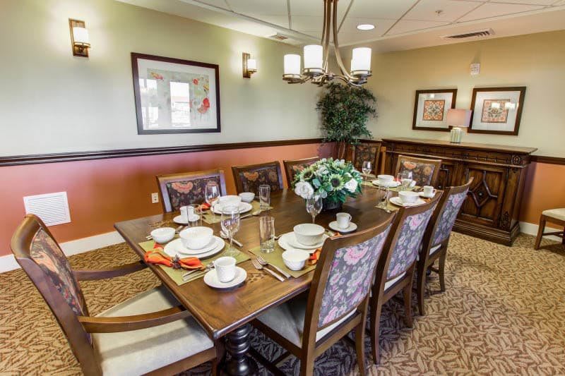 A formal dining room with a large table set for a meal, featuring elegant decor and a floral centerpiece.