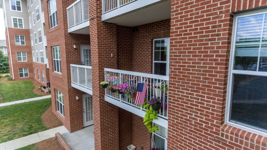 An apartment building with balconies decorated with flags and plants.