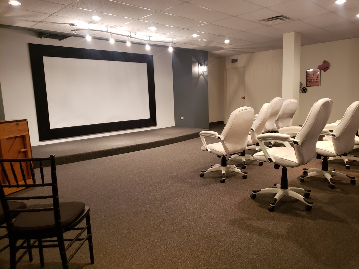 A conference room equipped with comfortable chairs and a large projector screen.