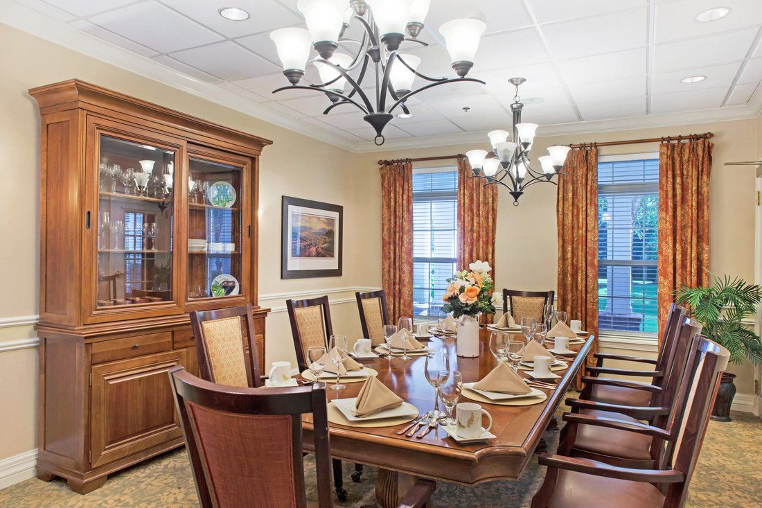 A formal dining room with an elegantly set table and chandeliers above.