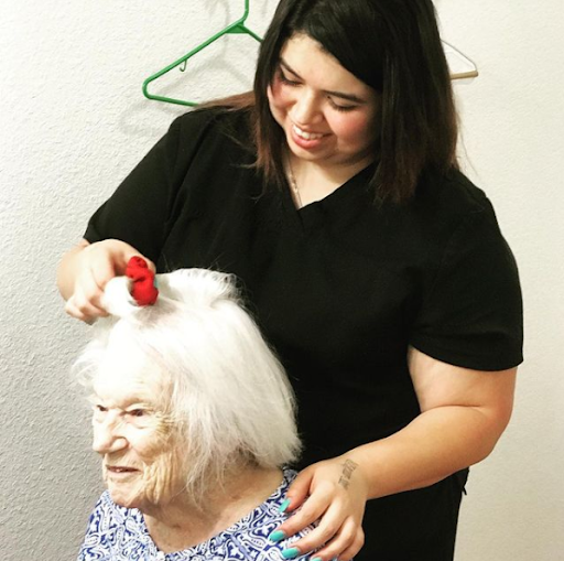 A caregiver is styling the hair of an elderly woman, showcasing a moment of personal care and attention.