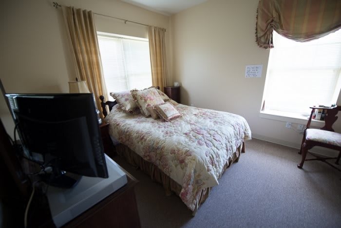 A cozy bedroom with a neatly made bed, pillows, and a television.