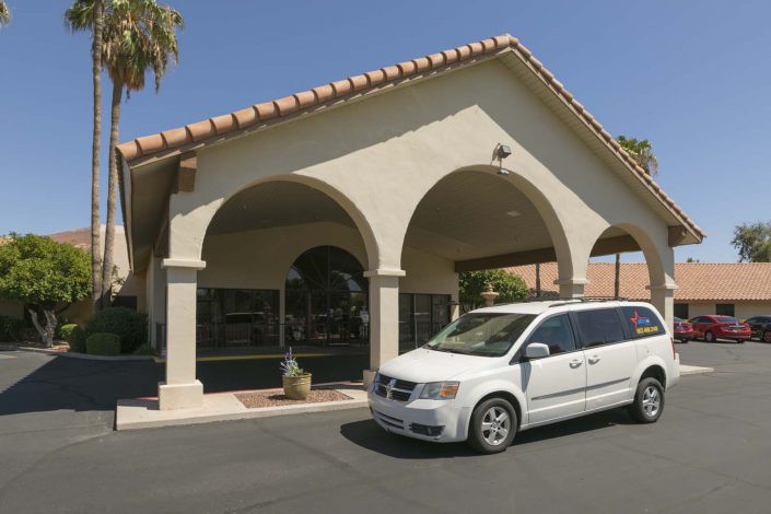 A white van parked in front of a building with arched entrances.