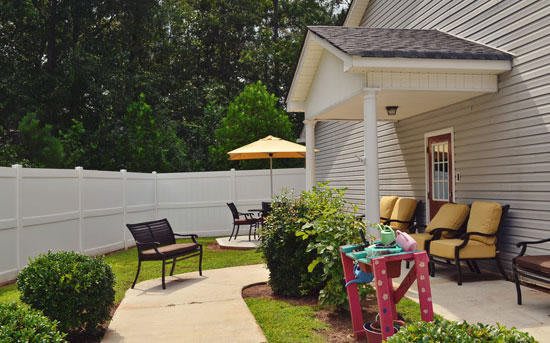 A cozy outdoor patio with a seating area and play space, surrounded by greenery.