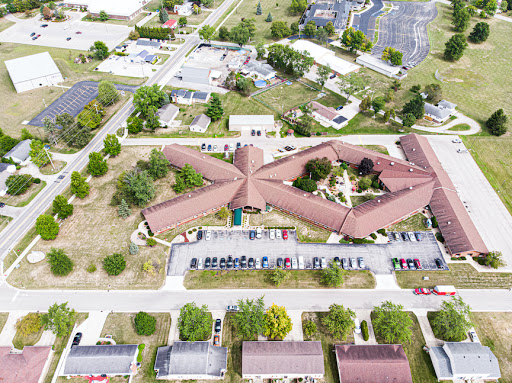 An aerial view of a uniquely designed building surrounded by greenery and a parking lot.