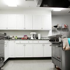 A spacious industrial kitchen with white cabinets and modern appliances.