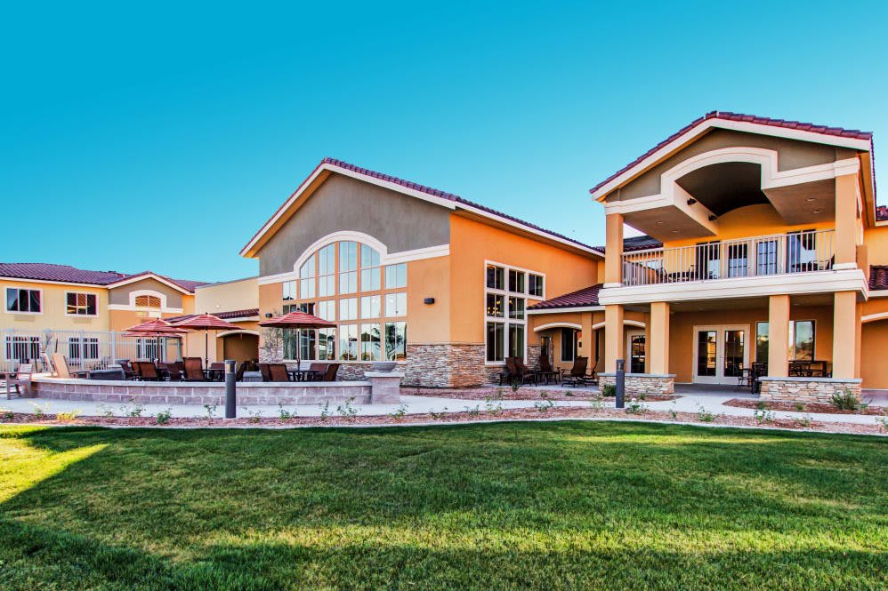 A spacious residential building with a neatly manicured lawn under a clear blue sky.