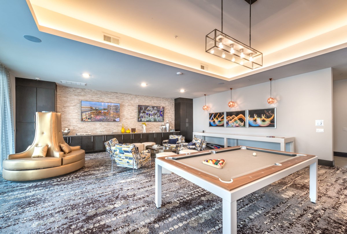 A modern game room featuring a stylish pool table, comfortable seating, and contemporary artwork.