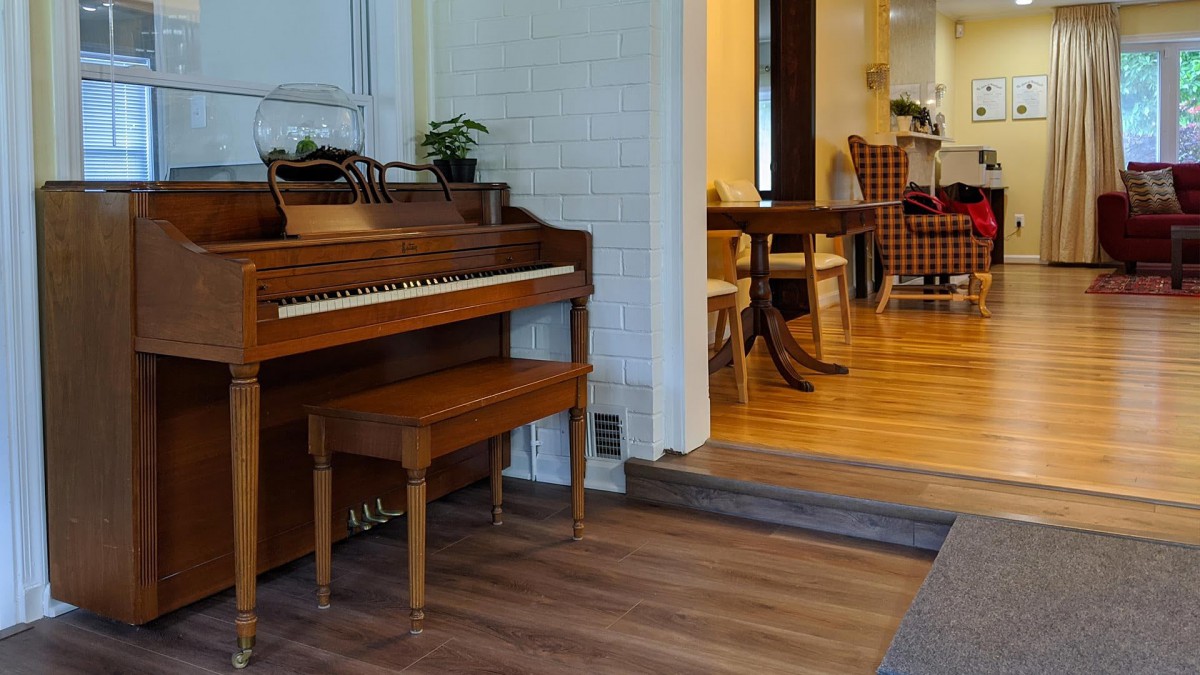 A cozy living space featuring a wooden piano and a view into the dining area.