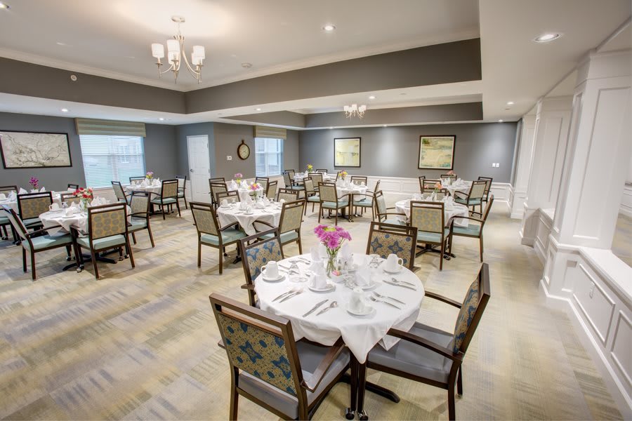 An elegant dining room with neatly arranged tables and chairs, set for a formal dining experience.