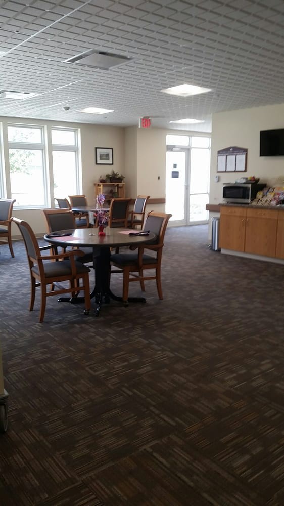 A well-lit dining area with tables and chairs, featuring a microwave and television.