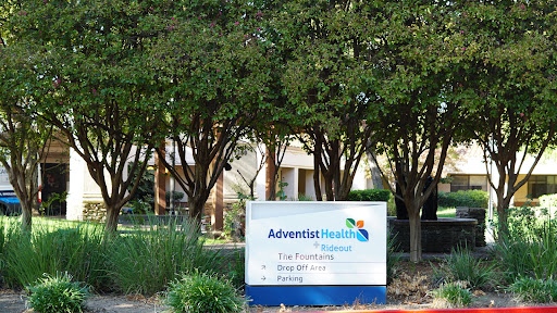A sign outside AdventHealth, surrounded by greenery.