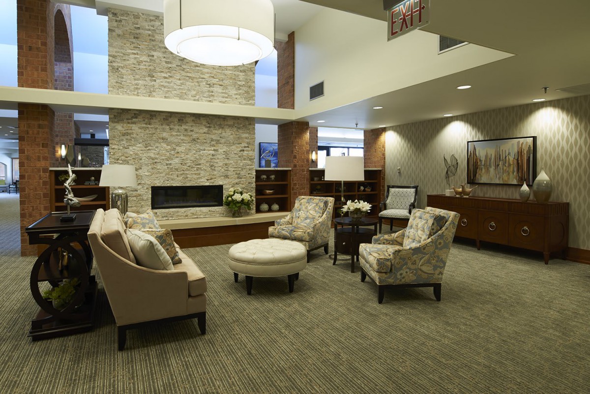A modern lobby with comfortable seating and a central fireplace.