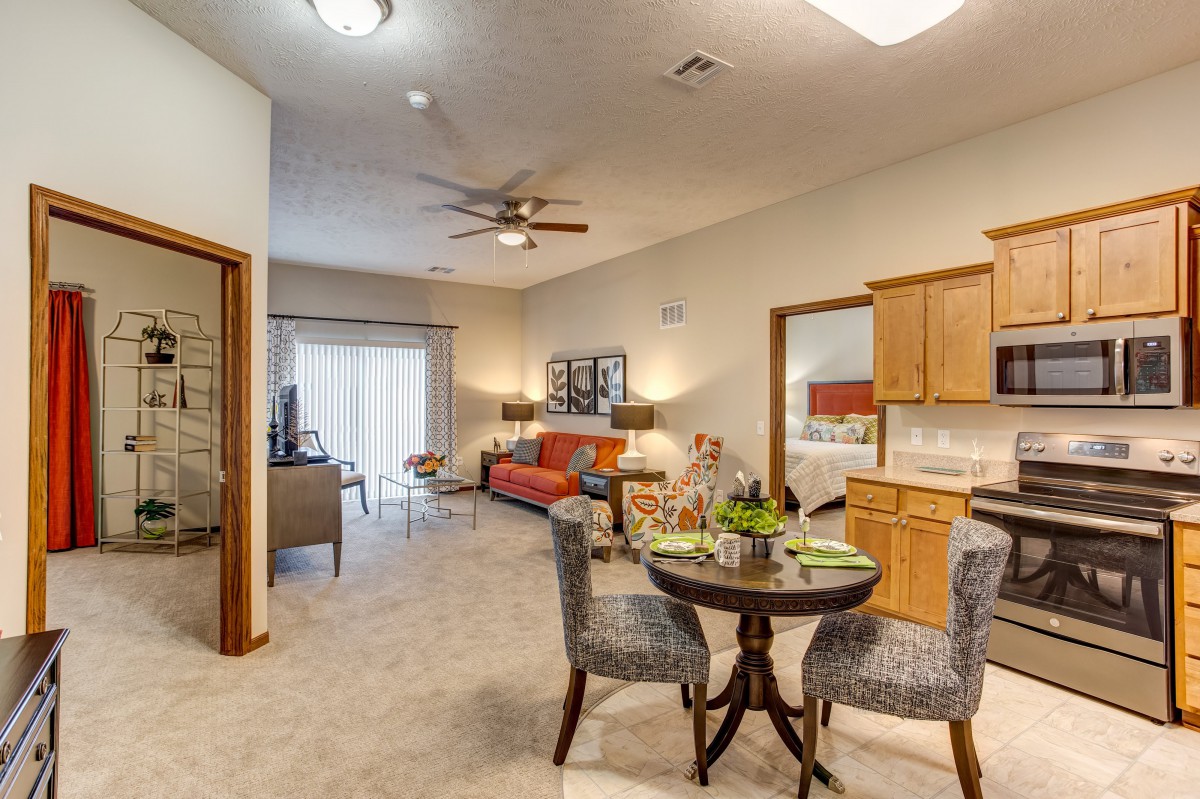 Open concept living space featuring a cozy sofa, dining table with chairs, and a kitchen area.