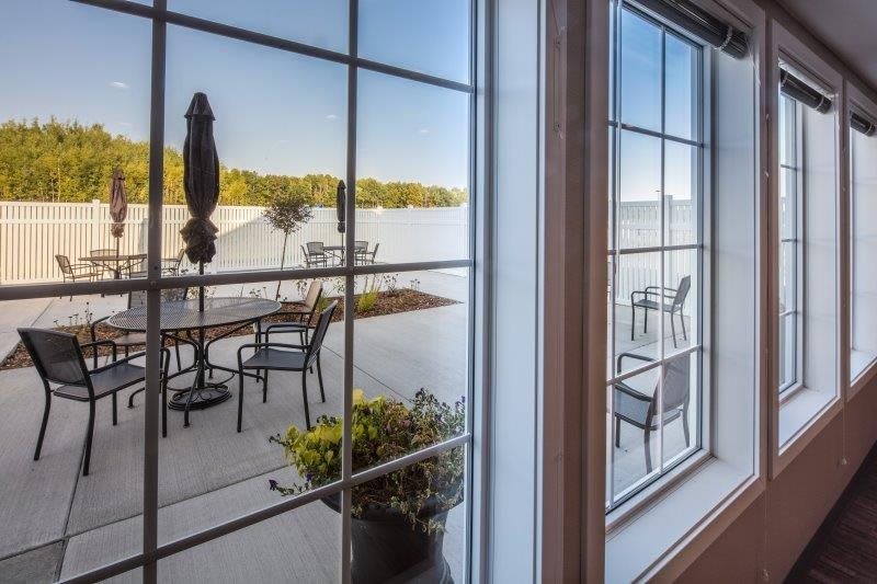 View of a lake and patio seating through a window.