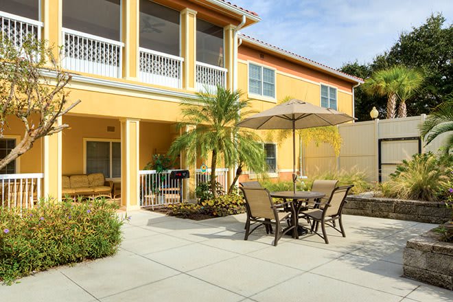 A sunny patio area with outdoor seating and a yellow building in the background.