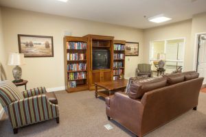A cozy living room with a television, bookshelves, and comfortable seating.