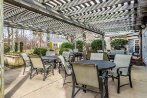 An inviting outdoor patio area with tables and chairs under a pergola.