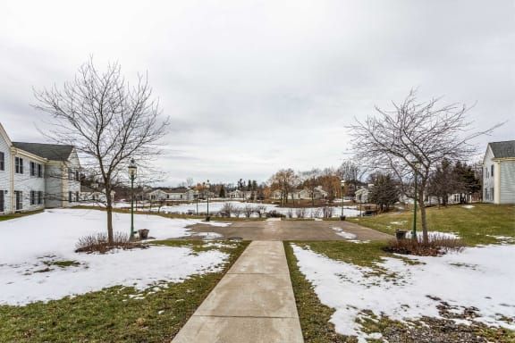 A park with a snow-lined pathway on a cloudy winter day.