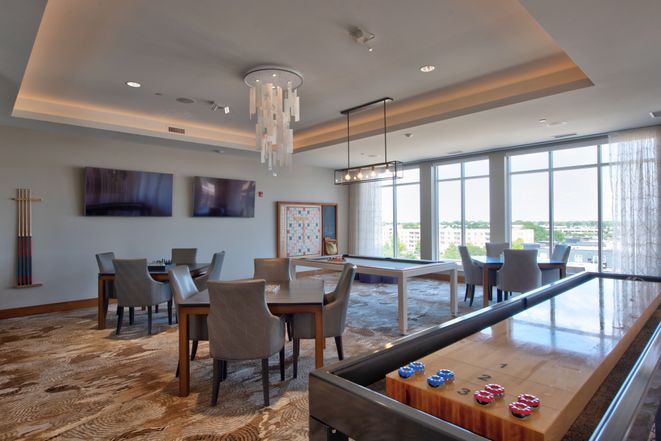 A modern game room with a foosball table, seating area, and large windows providing natural light.