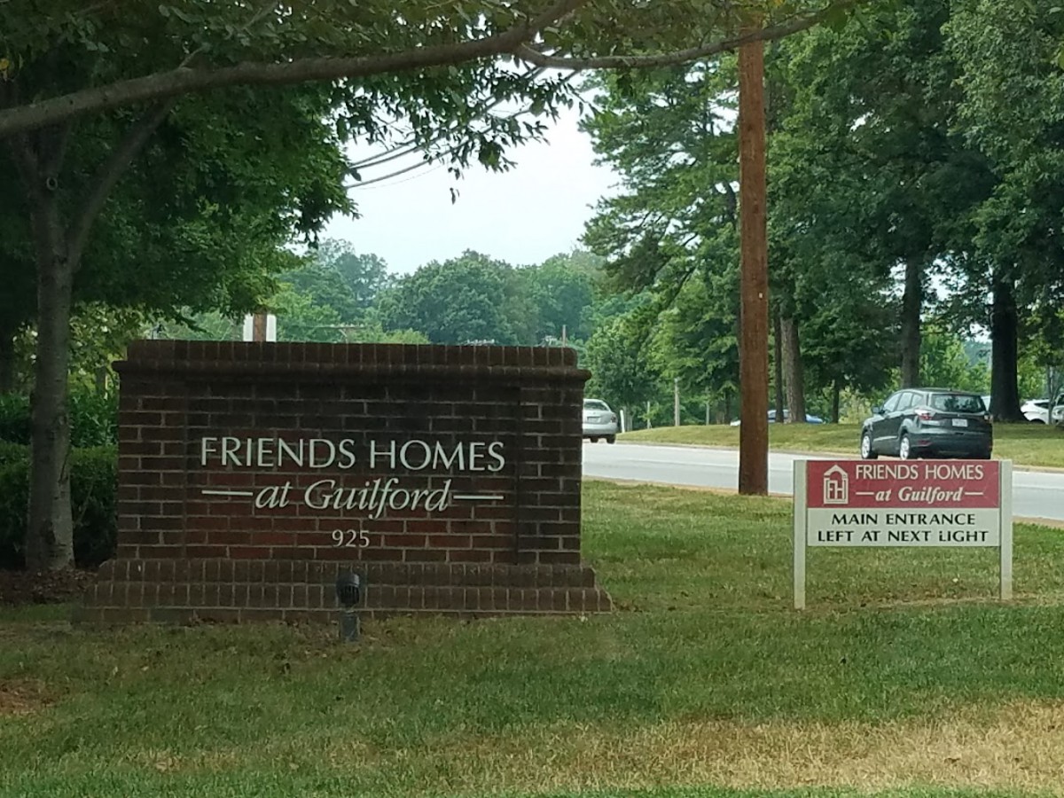 Entrance sign for Friends Homes at Guilford along a tree-lined road.