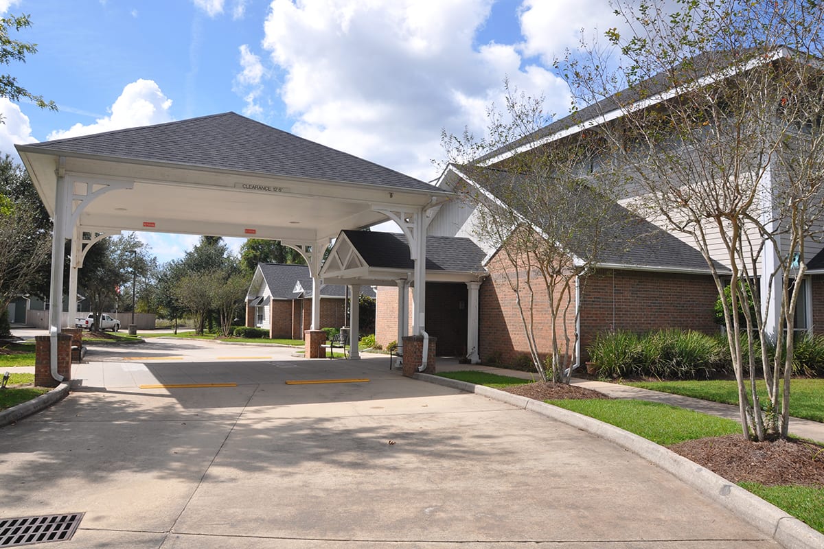 A suburban building with a covered driveway entrance and landscaped surroundings.