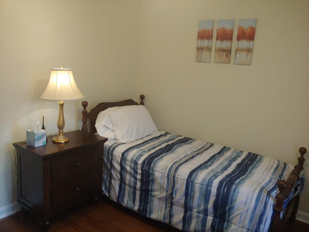 A cozy bedroom with a single bed, nightstand, and decorative wall art.