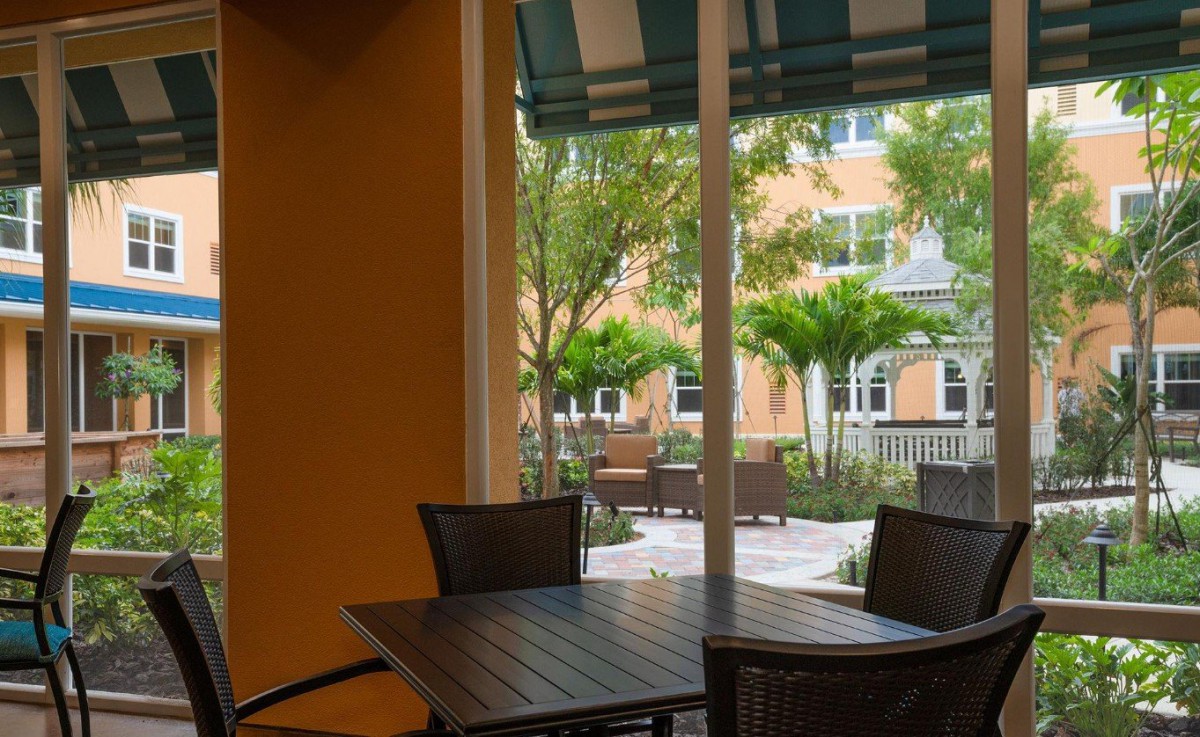 A cozy outdoor patio with a table and chairs overlooks a garden and building.