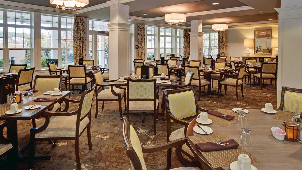 An elegant dining room with neatly set tables and chairs, ready for guests.