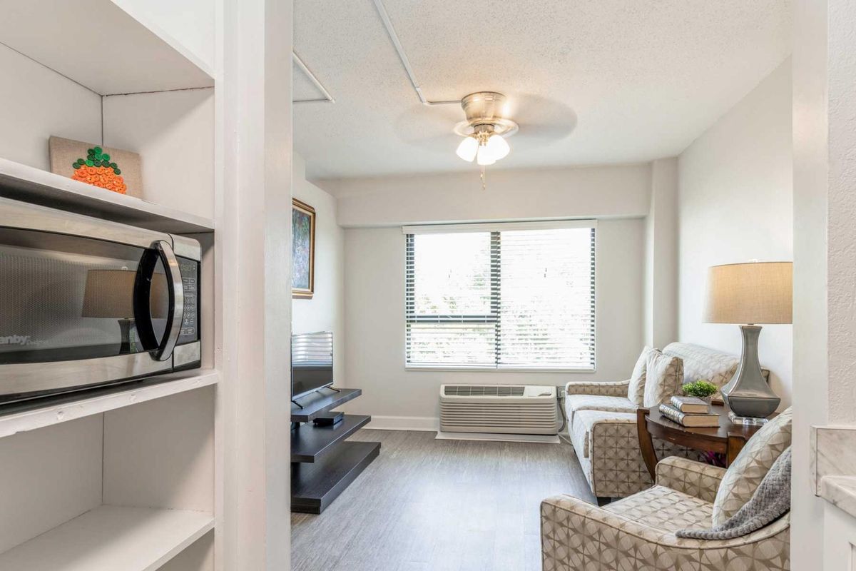 A modern apartment living room with a TV, chair, and a microwave.