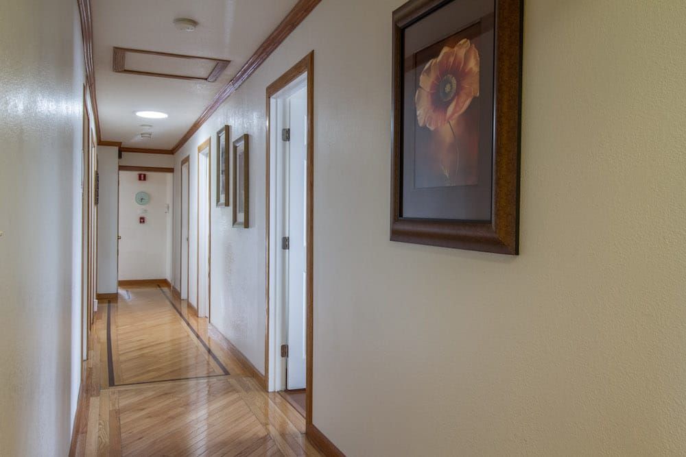 A well-lit hallway with framed artwork and wooden flooring.