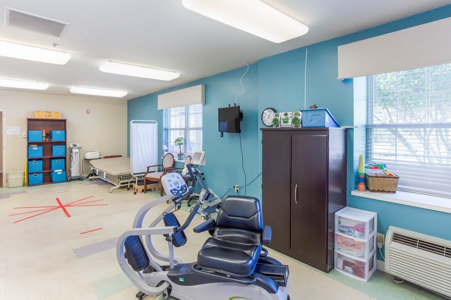 A well-equipped exercise room featuring a recumbent bike and various fitness equipment.