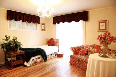 A cozy bedroom featuring a single bed and a patterned couch under a chandelier.