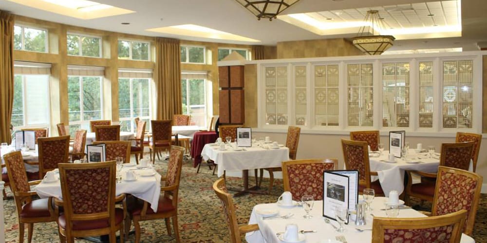 A cozy restaurant dining area with elegantly set tables and large windows.