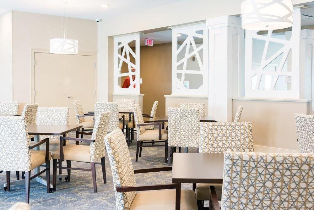 A modern dining area with patterned chairs and tables, featuring elegant lighting and decor.