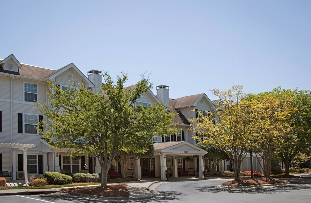 A suburban residential building surrounded by trees under a clear sky.